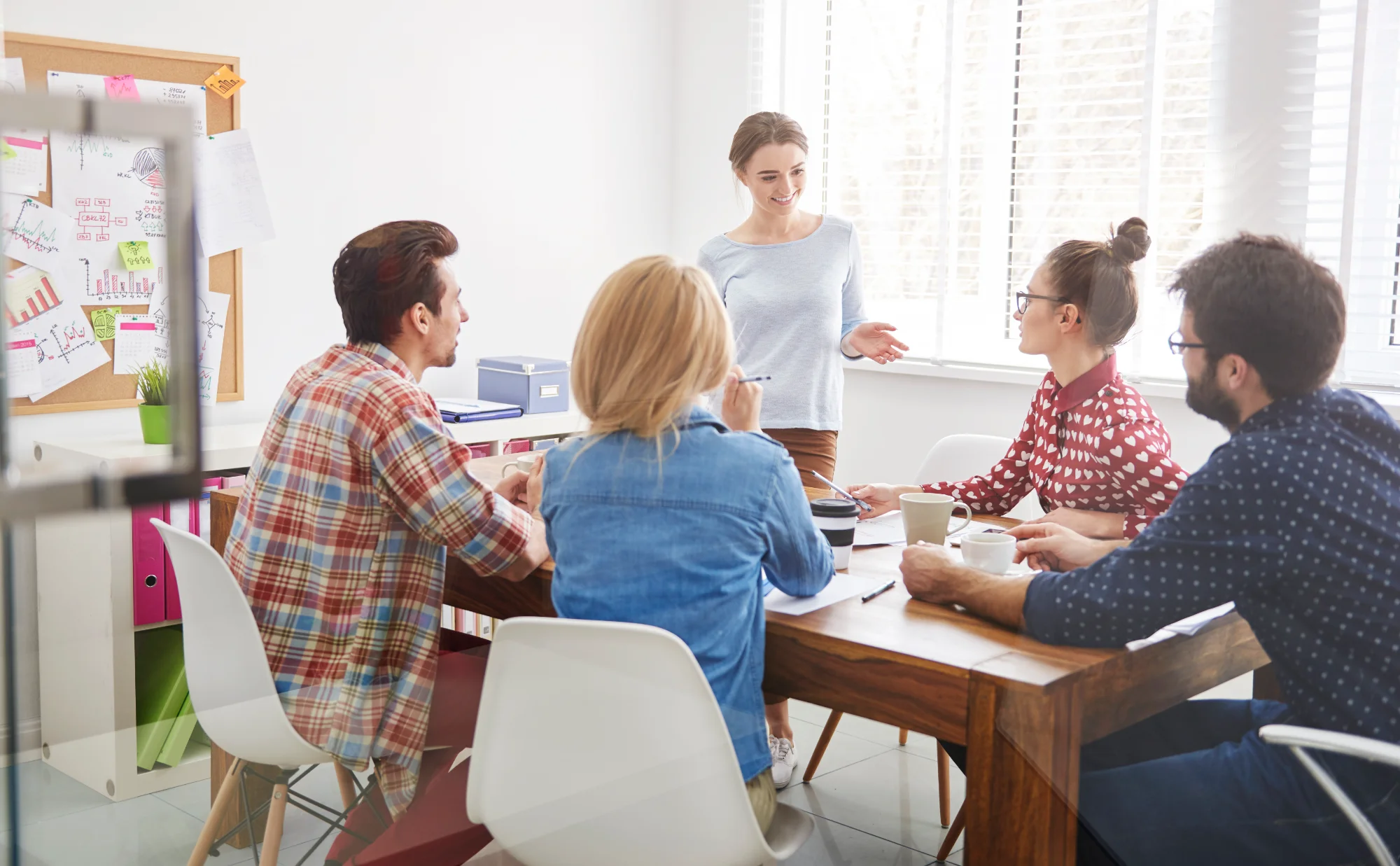 Un groupe de collaborateurs résout ensemble un cas pratique autour d'une table, sous le regard d'un formateur