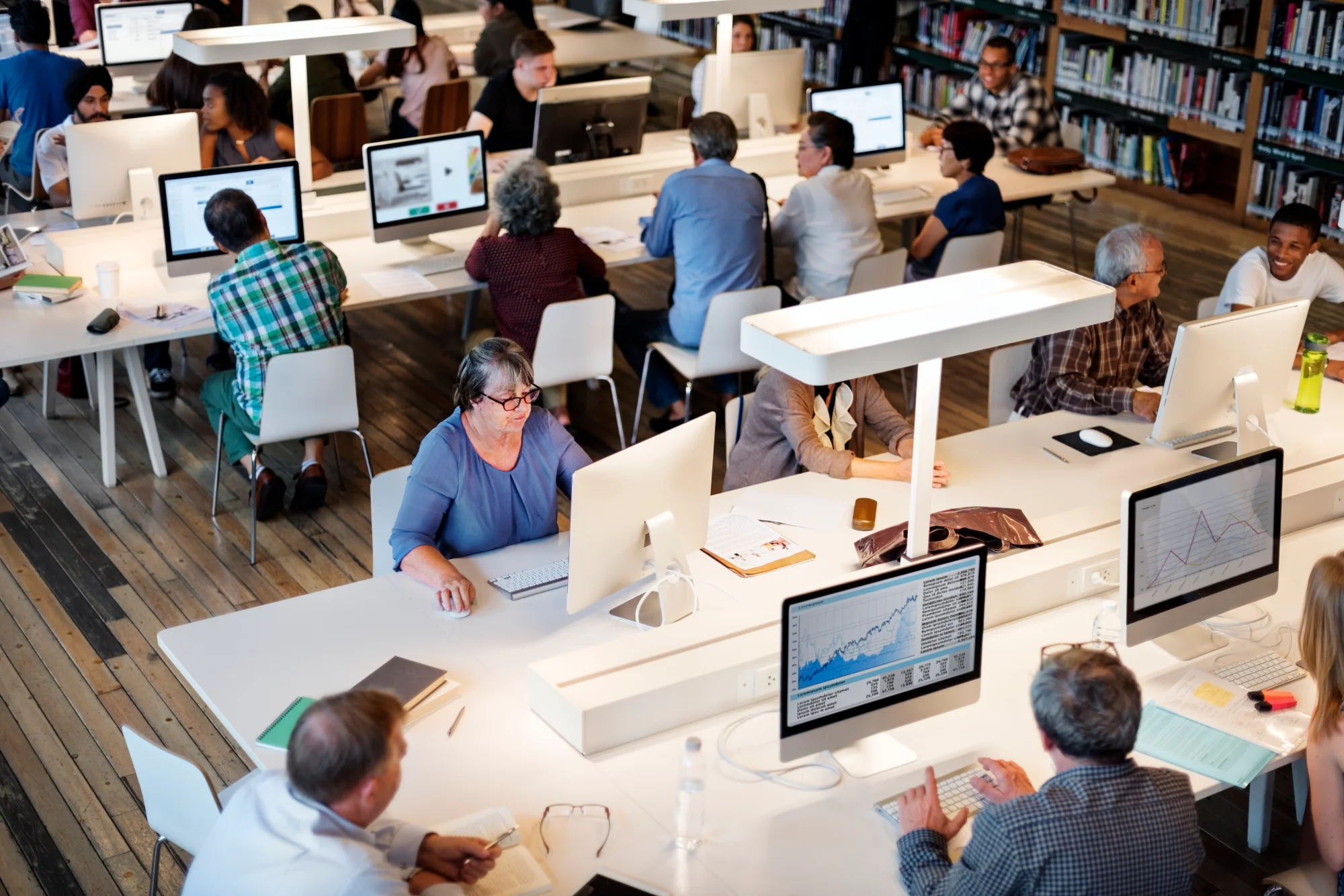 Profesionales de distintos departamentos trabajan con portátiles y paneles de datos en una mesa compartida de la oficina